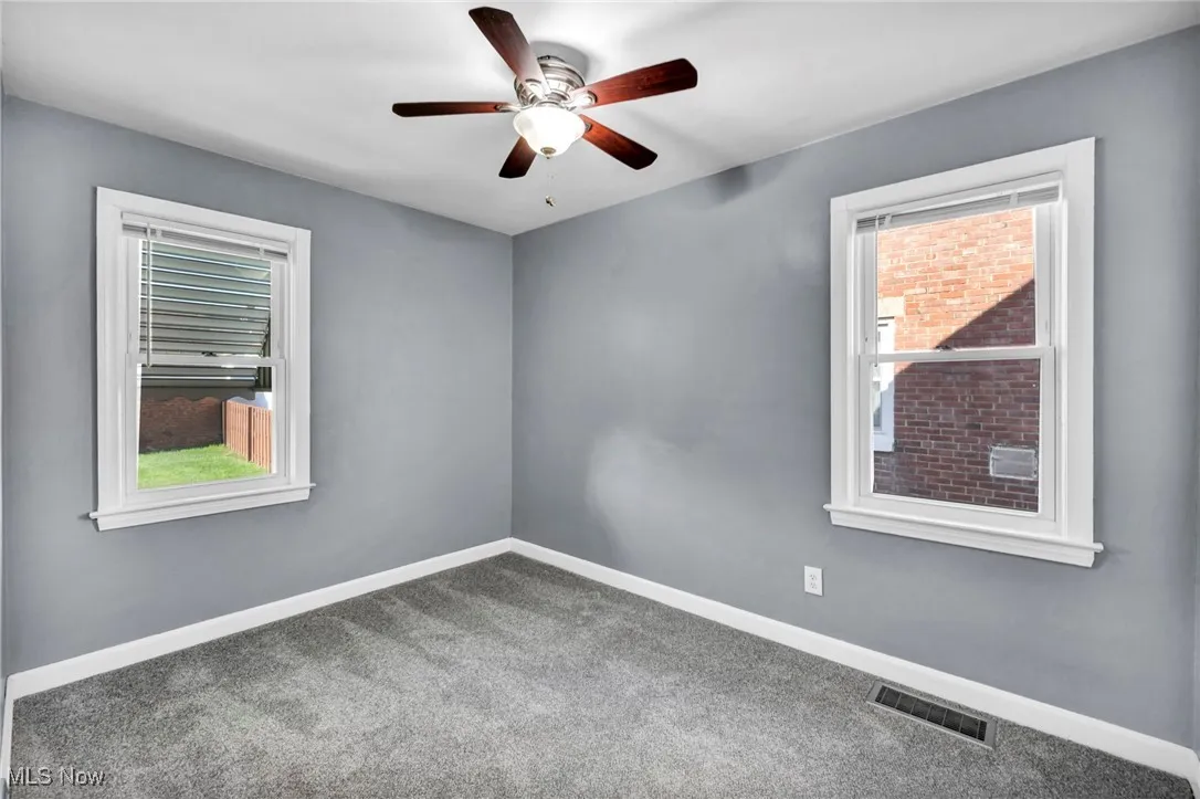 Carpeted spare room featuring baseboards and a ceiling fan