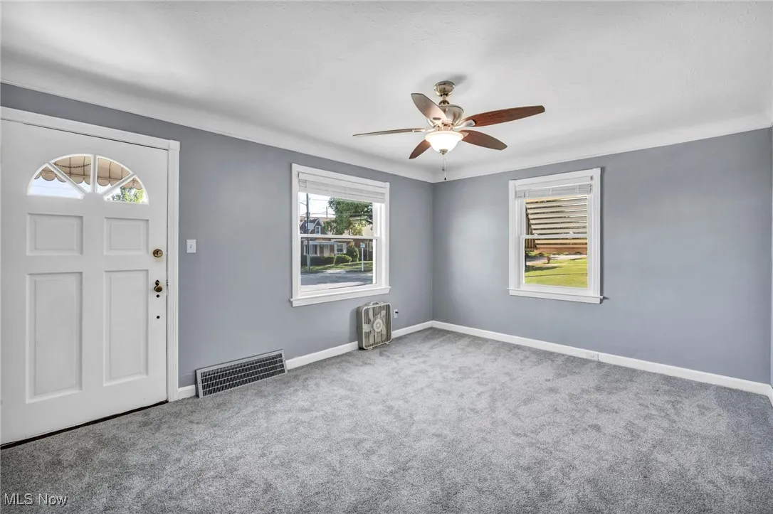 Foyer entrance featuring carpet and ceiling fan