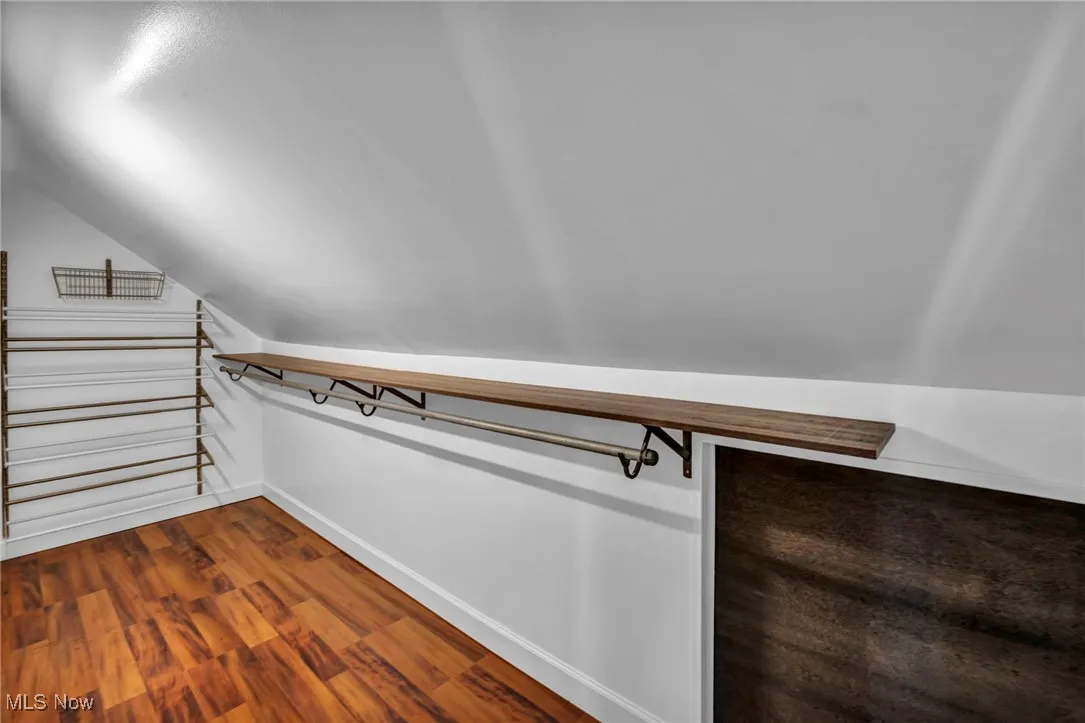 Spacious closet featuring dark wood-type flooring and vaulted ceiling