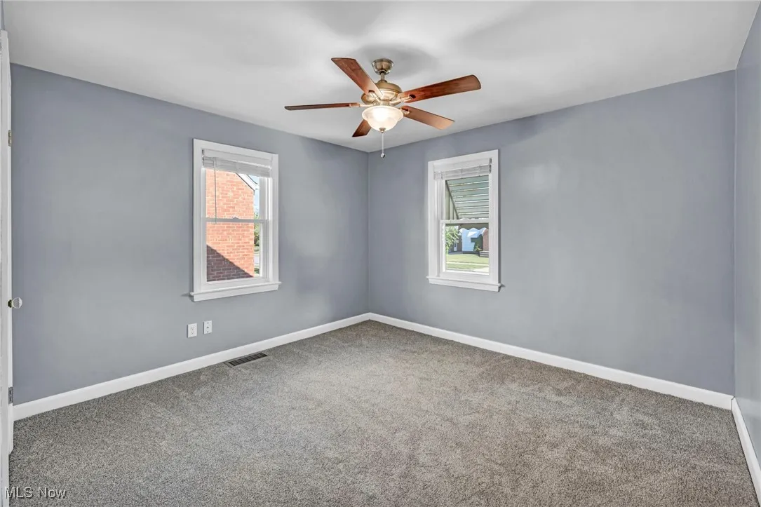 Carpeted empty room featuring baseboards and a ceiling fan