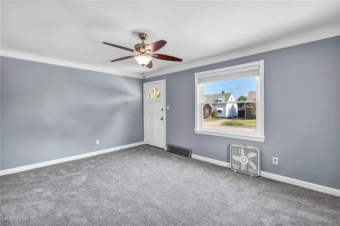 Carpeted spare room featuring a ceiling fan and baseboards