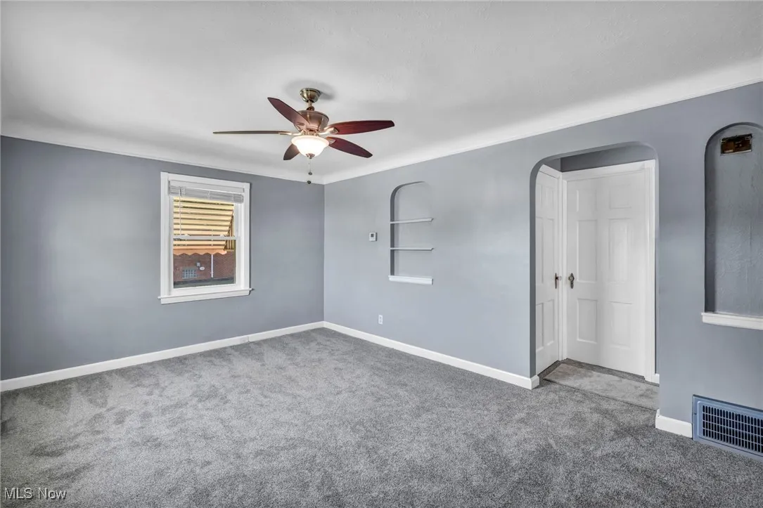 Empty room with a ceiling fan and carpet flooring