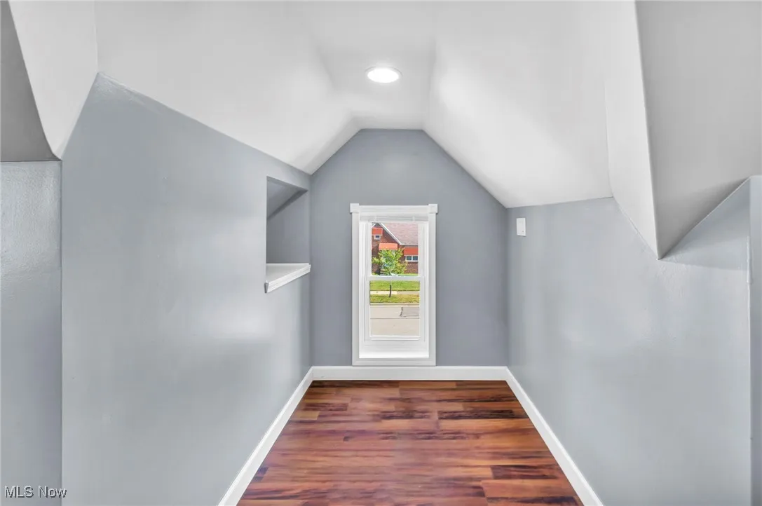 Additional living space featuring wood finished floors and vaulted ceiling