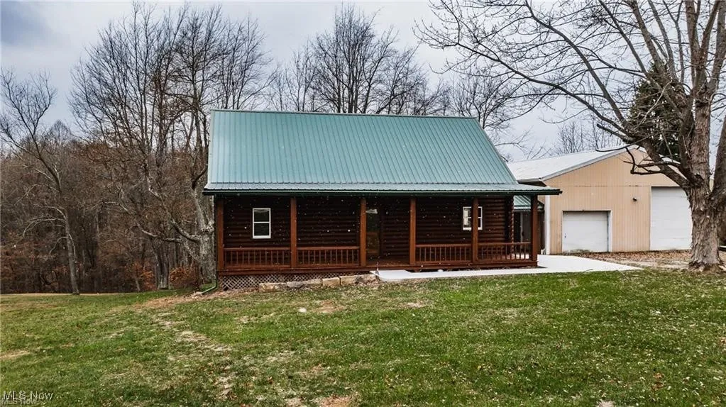 View of front facade with a porch, a metal roof, a garage, and a front lawn