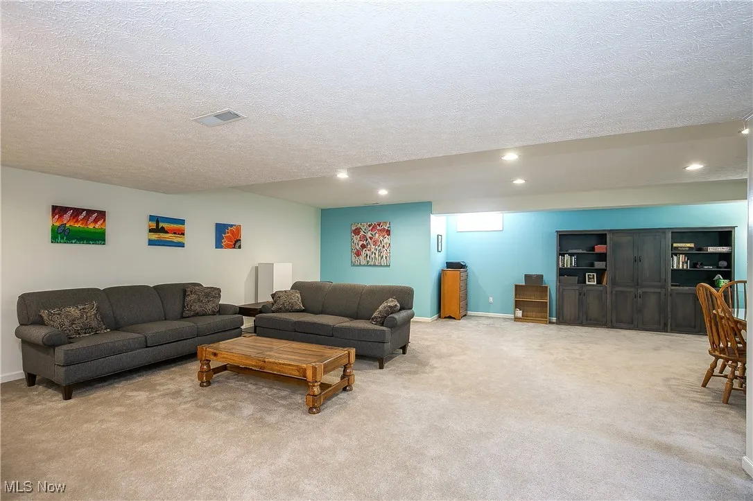 Living area with a textured ceiling, light carpet, and recessed lighting