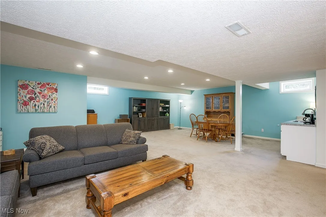 Living area featuring light colored carpet, plenty of natural light, a textured ceiling, and recessed lighting