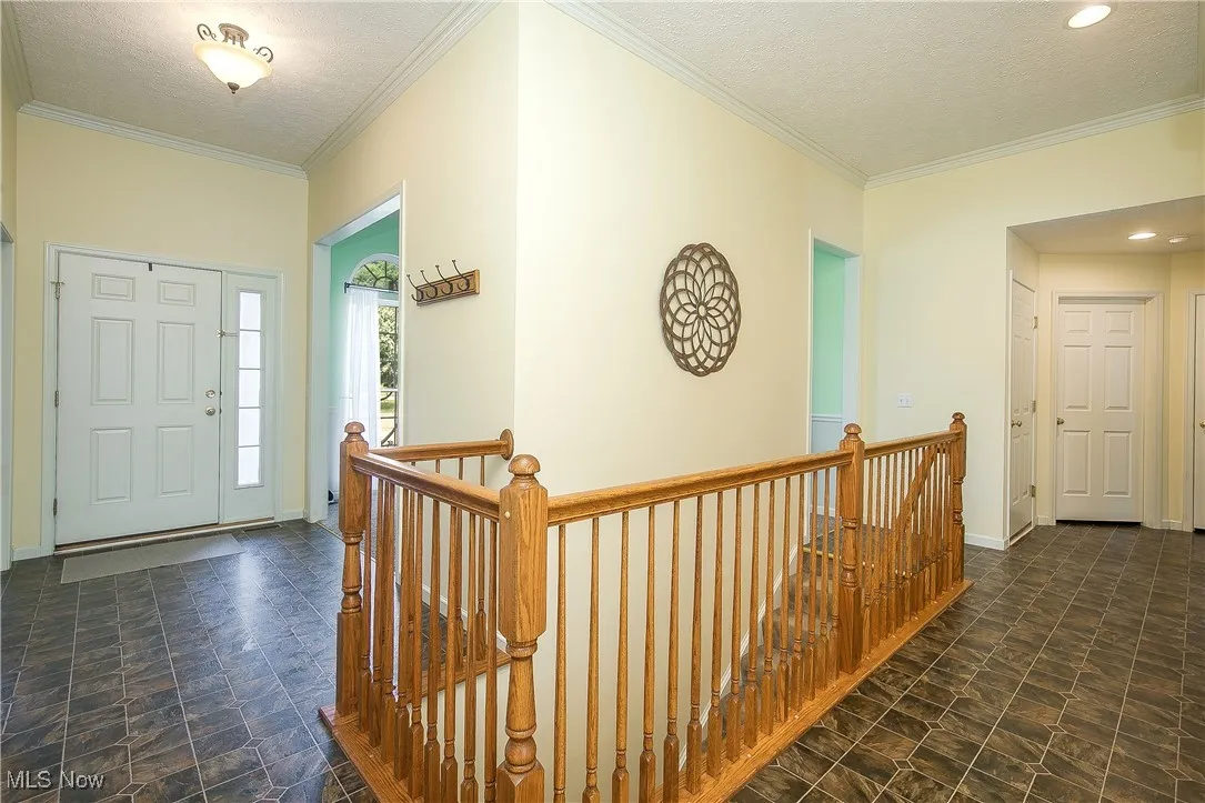 Entryway with crown molding, stone finish floors, a textured ceiling, and recessed lighting