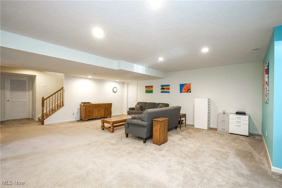 Living area with a textured ceiling, carpet, stairway, and recessed lighting