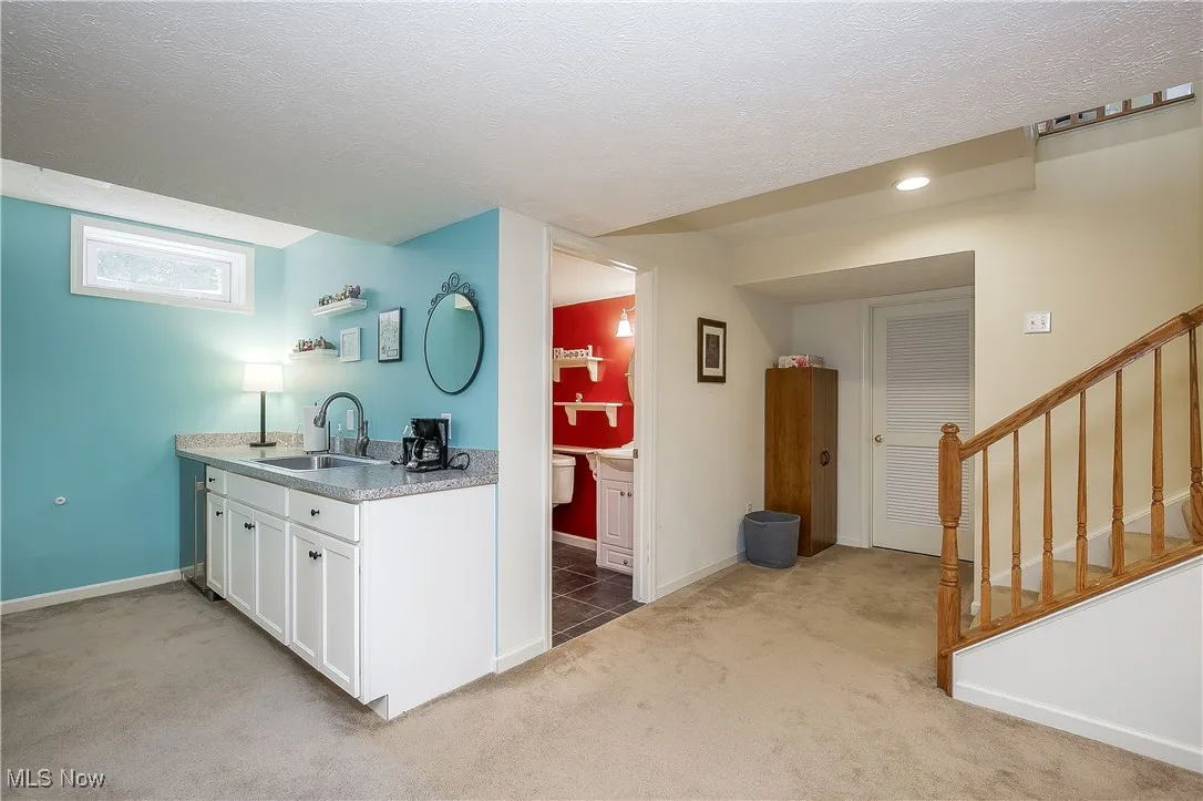 Kitchen with light carpet, a textured ceiling, white cabinetry, light countertops, and light tile patterned floors