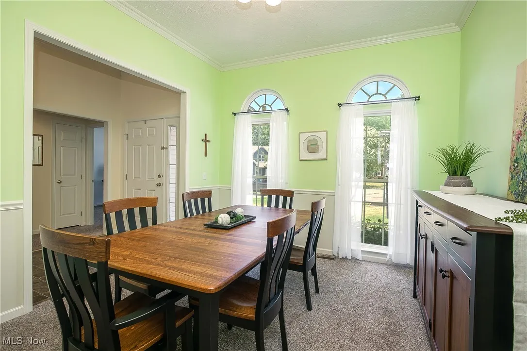 Dining area with light colored carpet and ornamental molding