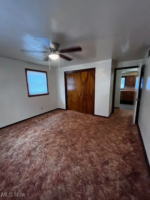 Unfurnished bedroom featuring carpet floors, a closet, and ceiling fan