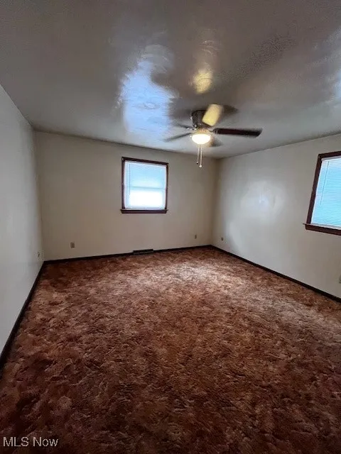 Spare room with a ceiling fan, carpet floors, and a textured ceiling