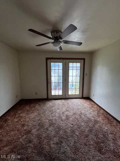 Carpeted empty room featuring ceiling fan and baseboards