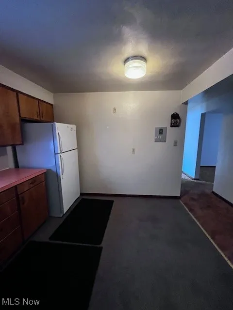 Kitchen featuring refrigerator and light carpet