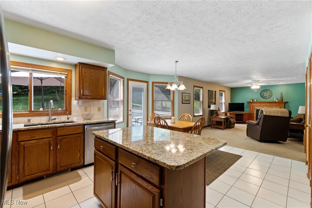 Kitchen featuring light tile patterned flooring, decorative backsplash, a chandelier, stainless steel appliances, and a textured ceiling