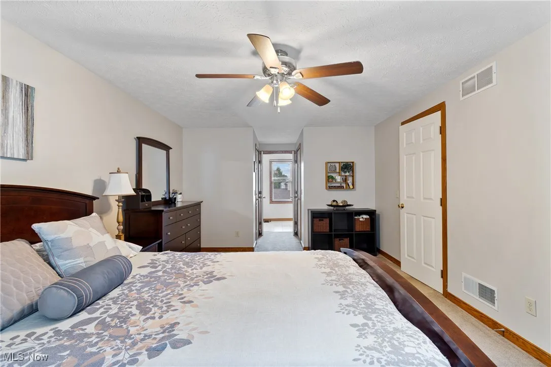 Carpeted bedroom featuring a textured ceiling and ceiling fan