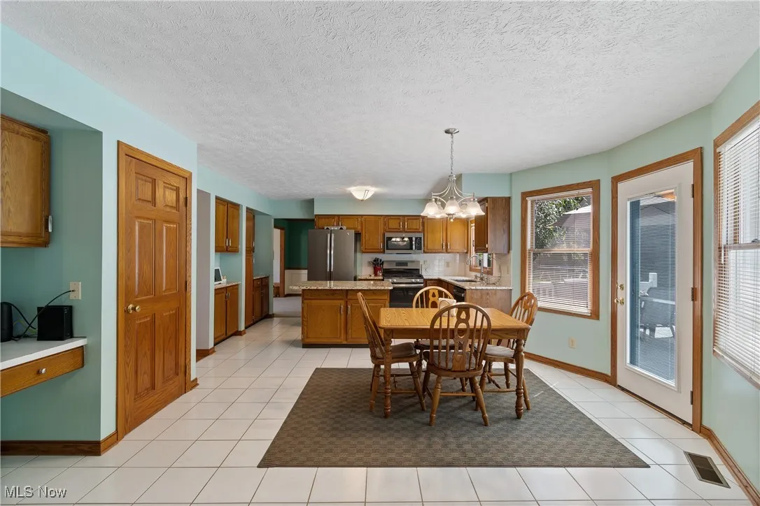 Dining room with a chandelier, light tile patterned flooring, and a textured ceiling