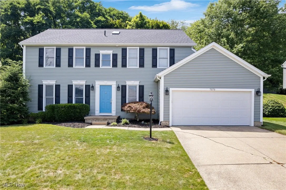 Colonial house with an attached garage, a front lawn, and concrete driveway