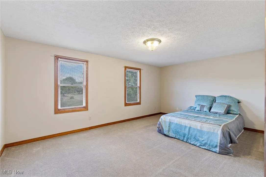 Carpeted bedroom with a textured ceiling and baseboards