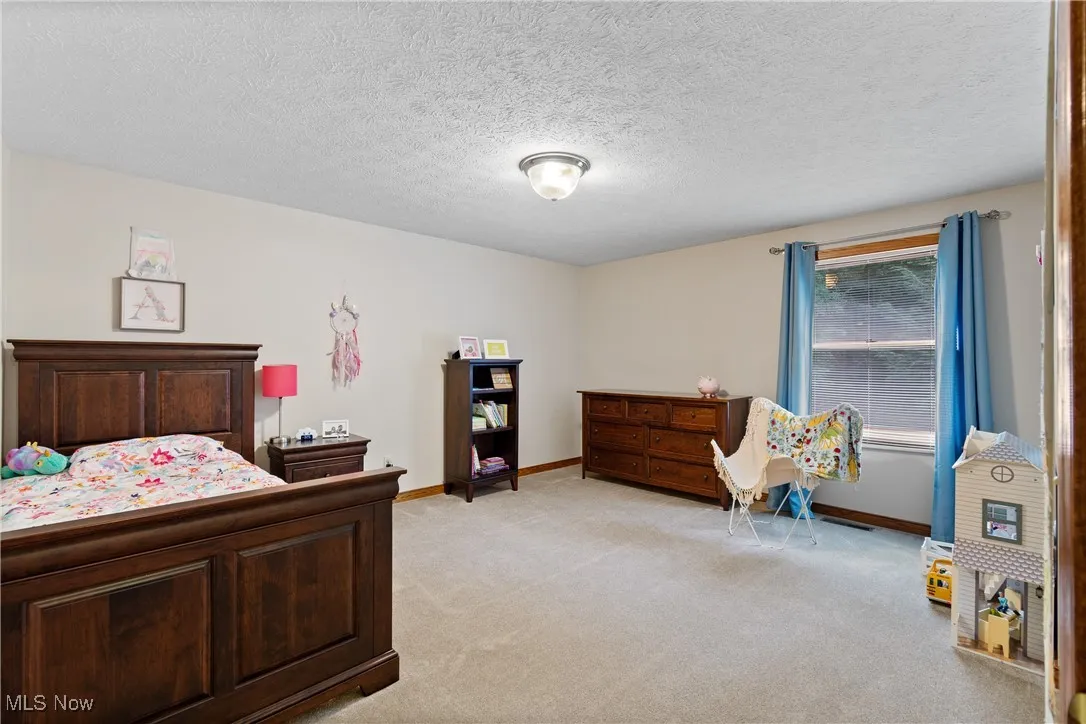 Bedroom featuring light carpet and a textured ceiling