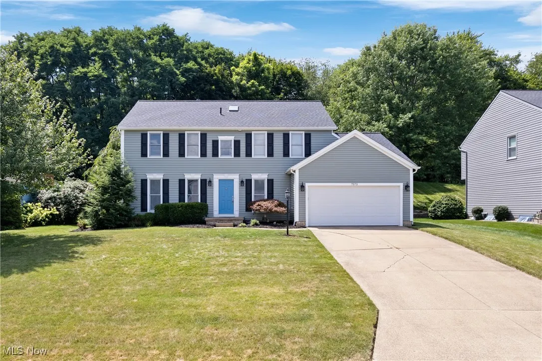 Colonial house with an attached garage, driveway, and a front yard