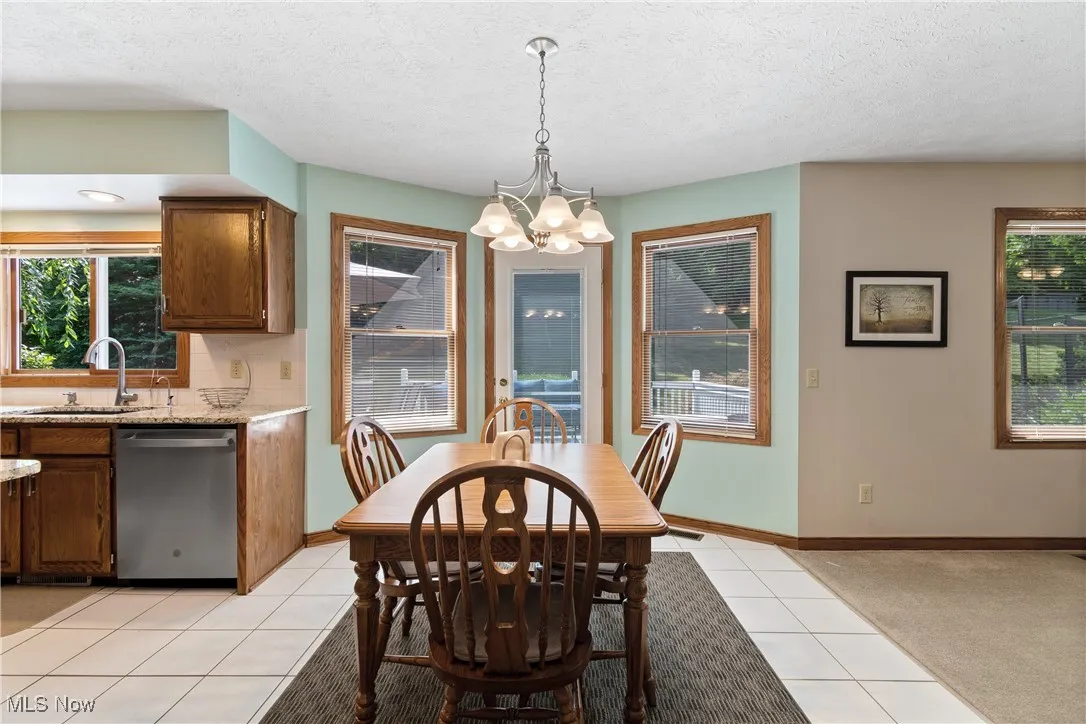Dining space featuring plenty of natural light, light tile patterned flooring, a chandelier, a textured ceiling, and light carpet