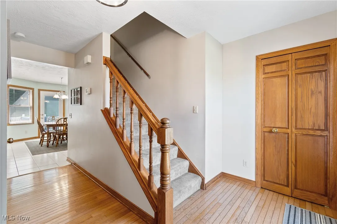 Staircase with hardwood / wood-style flooring, a chandelier, and a textured ceiling
