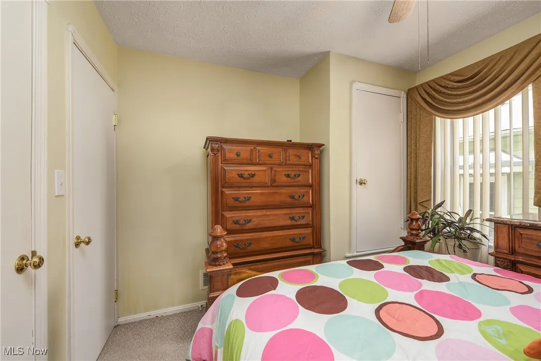 Bedroom featuring a textured ceiling, carpet flooring, and a ceiling fan