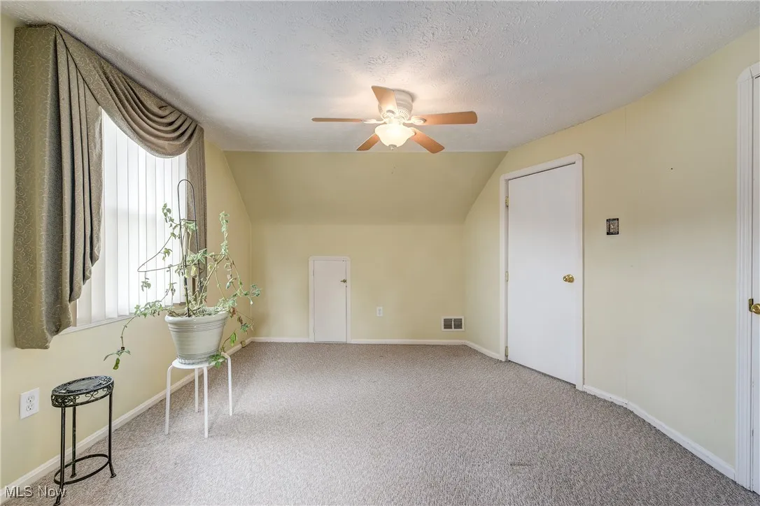 Additional living space featuring ceiling fan, lofted ceiling, carpet floors, and a textured ceiling