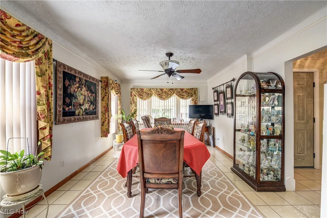 Dining room featuring a ceiling fan, crown molding, a textured ceiling, and light tile patterned floors
