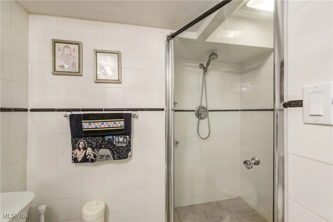 Full bath with a shower stall, tile walls, and a textured ceiling