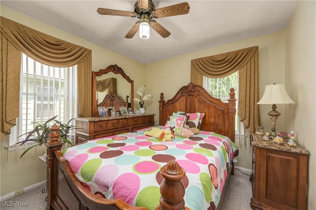 Bedroom with light colored carpet, ceiling fan, and a textured ceiling