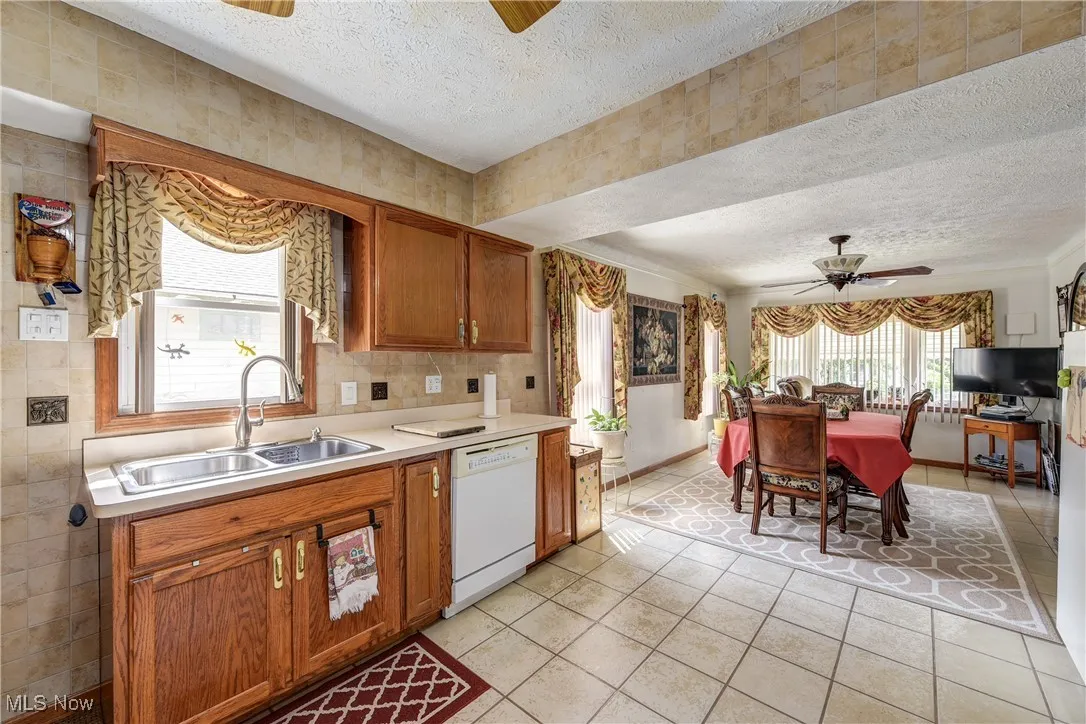 Kitchen featuring a ceiling fan, plenty of natural light, a textured ceiling, light countertops, and dishwasher