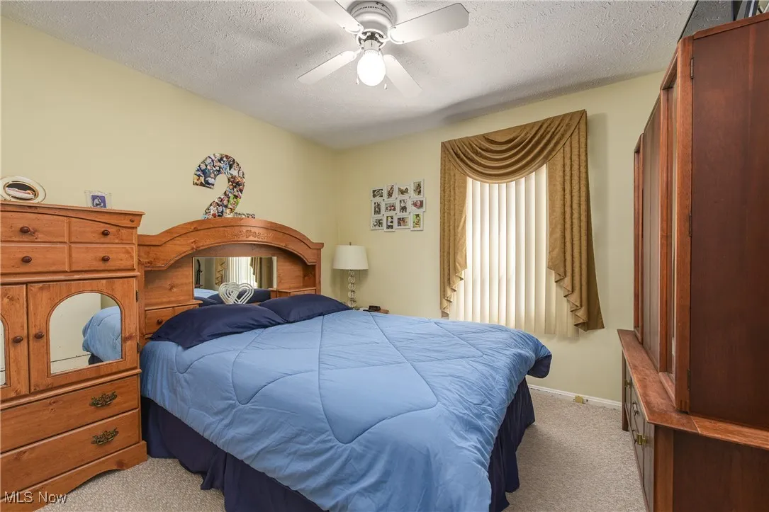 Bedroom with light carpet, a textured ceiling, and ceiling fan