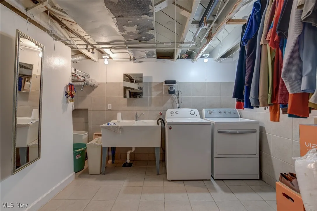 Washroom featuring separate washer and dryer, tile walls, and light tile patterned flooring
