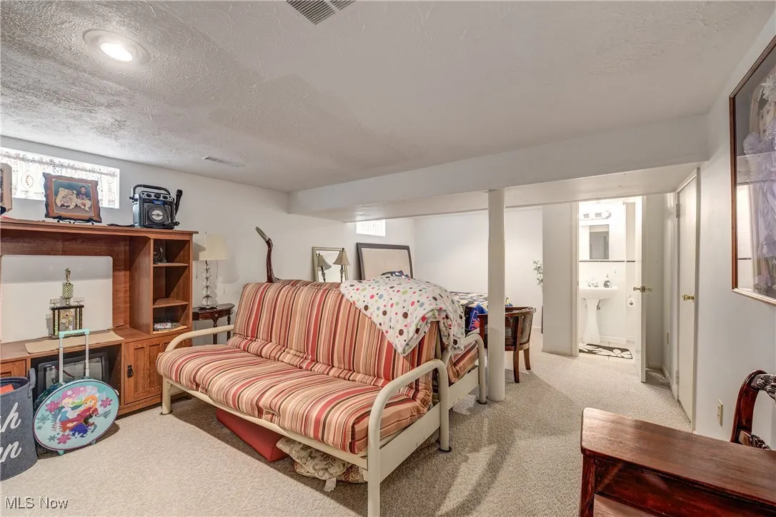 Bedroom featuring a textured ceiling, light colored carpet, and ensuite bath