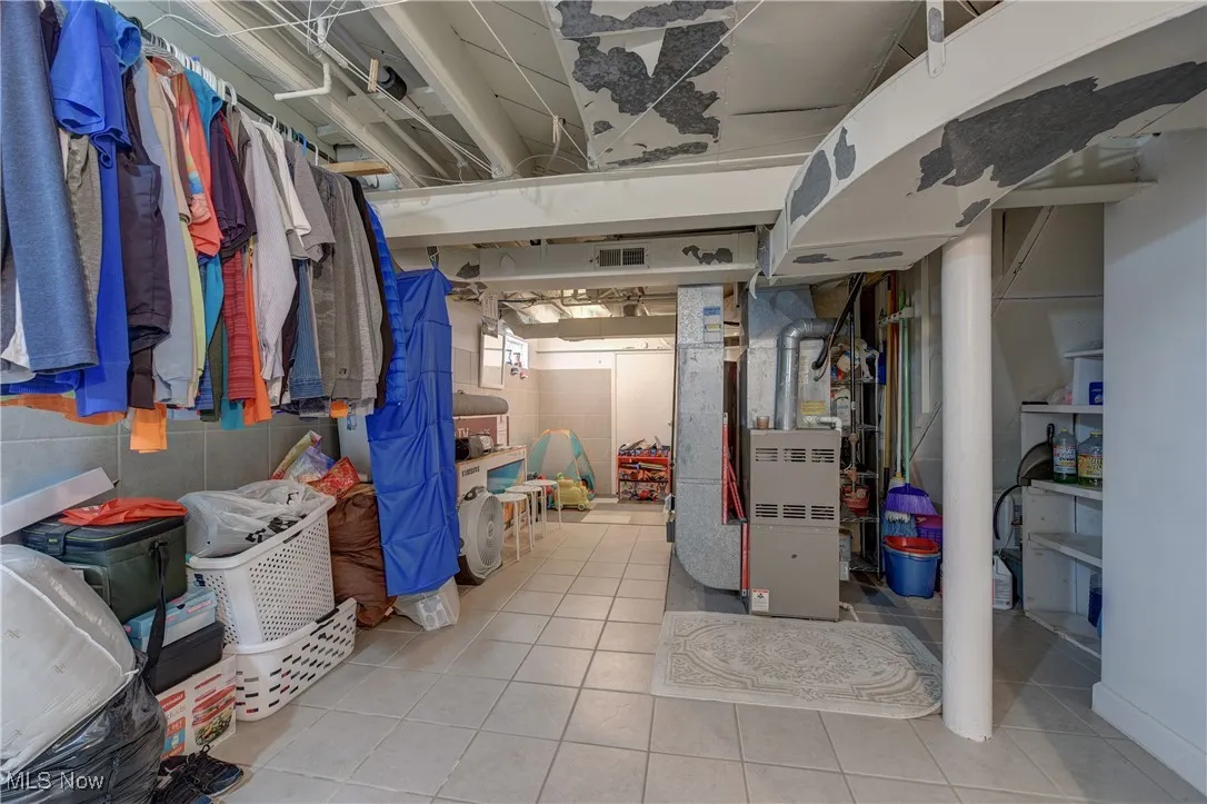 Unfinished basement featuring heating unit and tile patterned floors