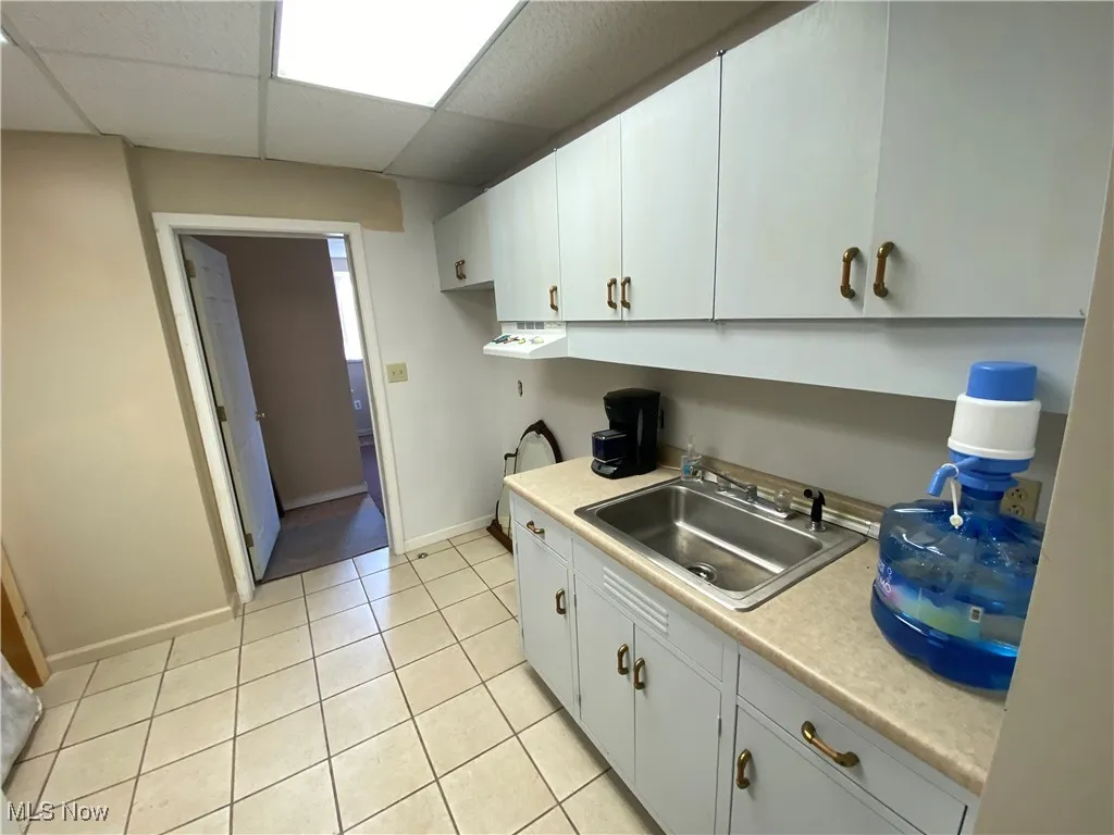 Kitchen with sink, white cabinetry, a paneled ceiling, and light tile patterned floors