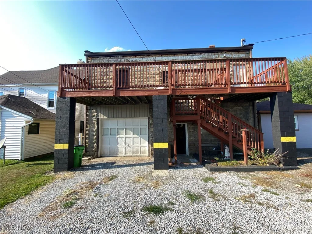 Rear view of property with a deck and a garage