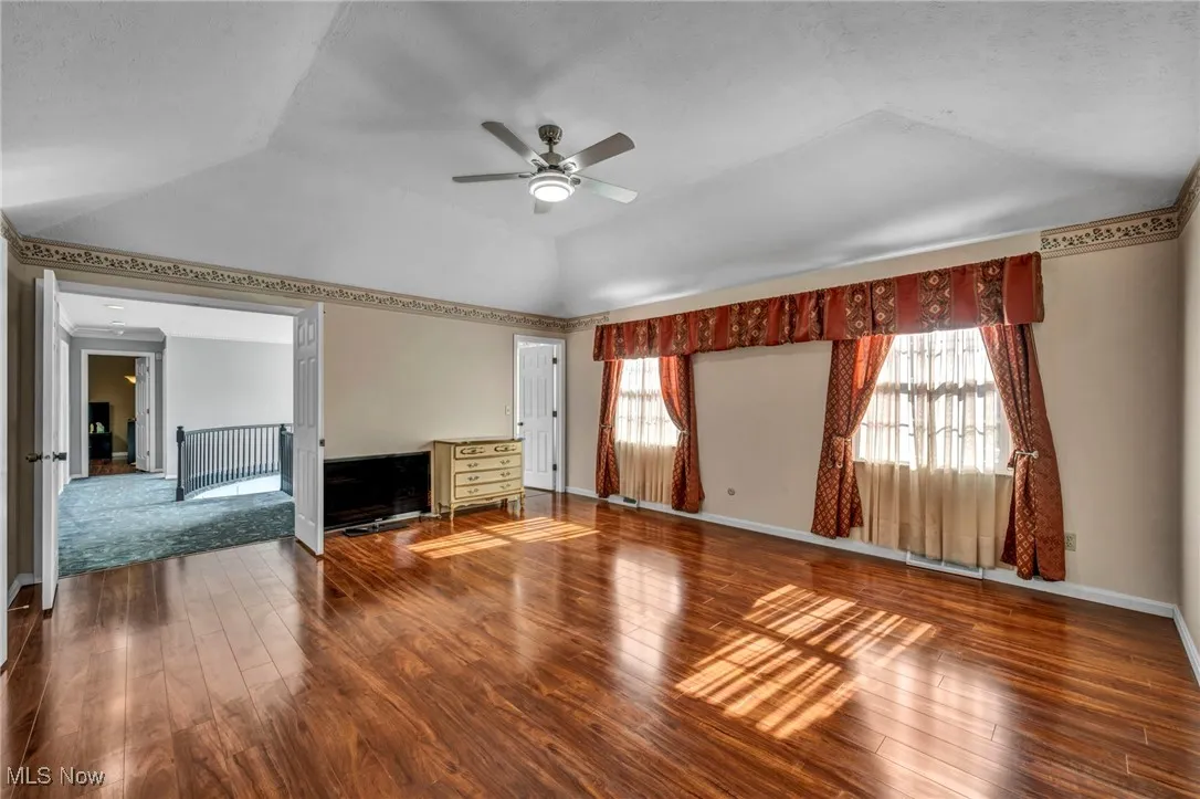 Unfurnished living room with wood-type flooring, a ceiling fan, and vaulted ceiling