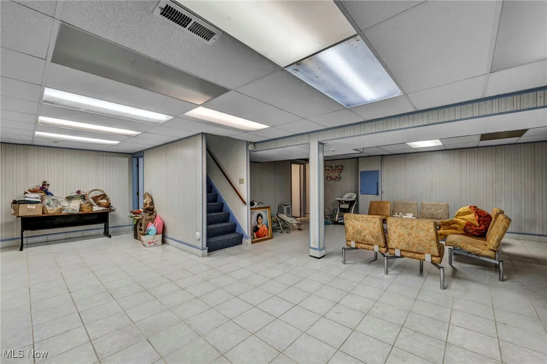 Finished below grade area featuring a paneled ceiling and stairway