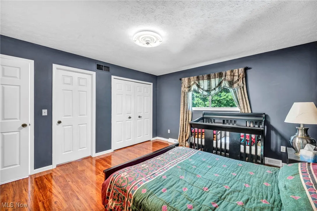 Bedroom with a textured ceiling, wood finished floors, and a closet