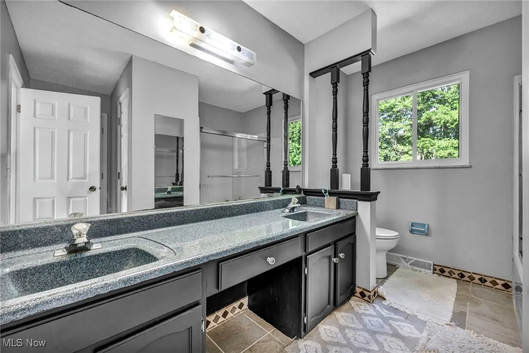 Full bathroom featuring double vanity and a stall shower