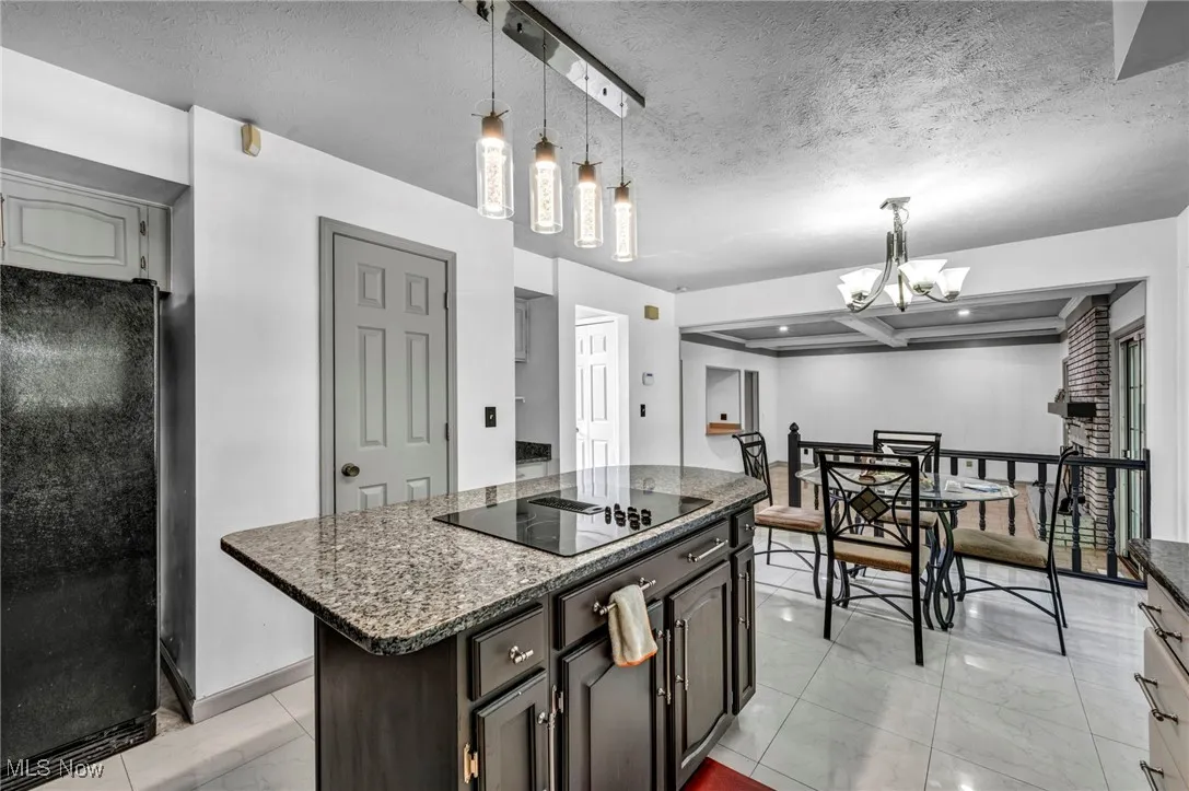 Kitchen featuring a chandelier, black appliances, coffered ceiling, beamed ceiling, and a textured ceiling