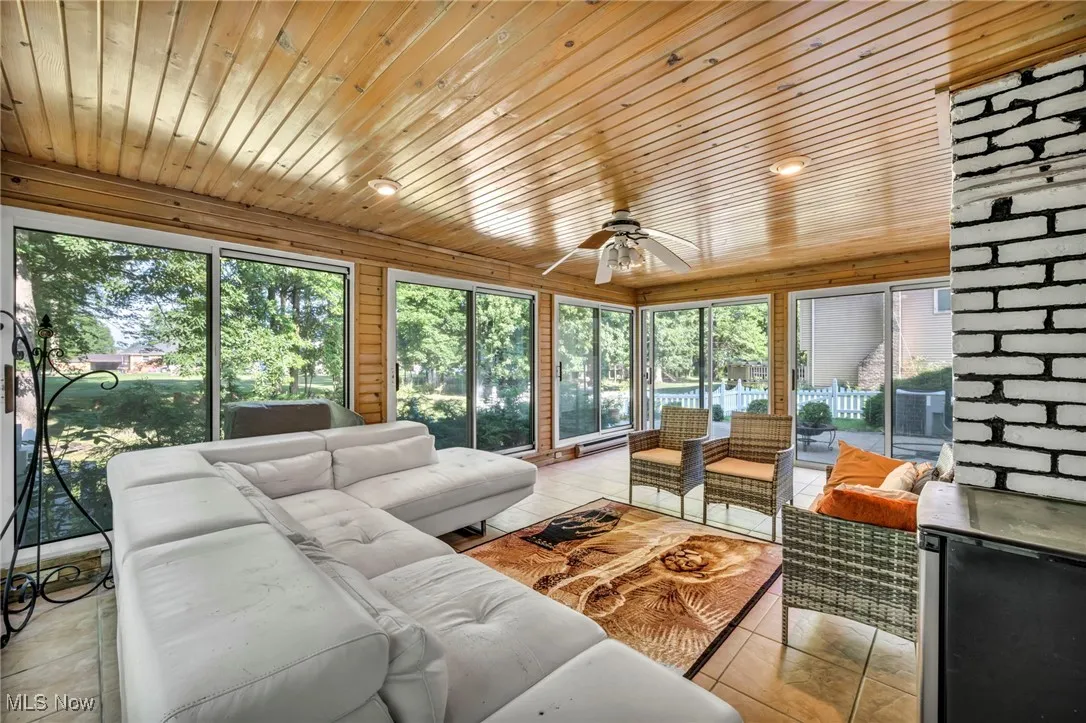 Living room with a ceiling fan, healthy amount of natural light, wooden ceiling, light tile patterned flooring, and a baseboard heating unit