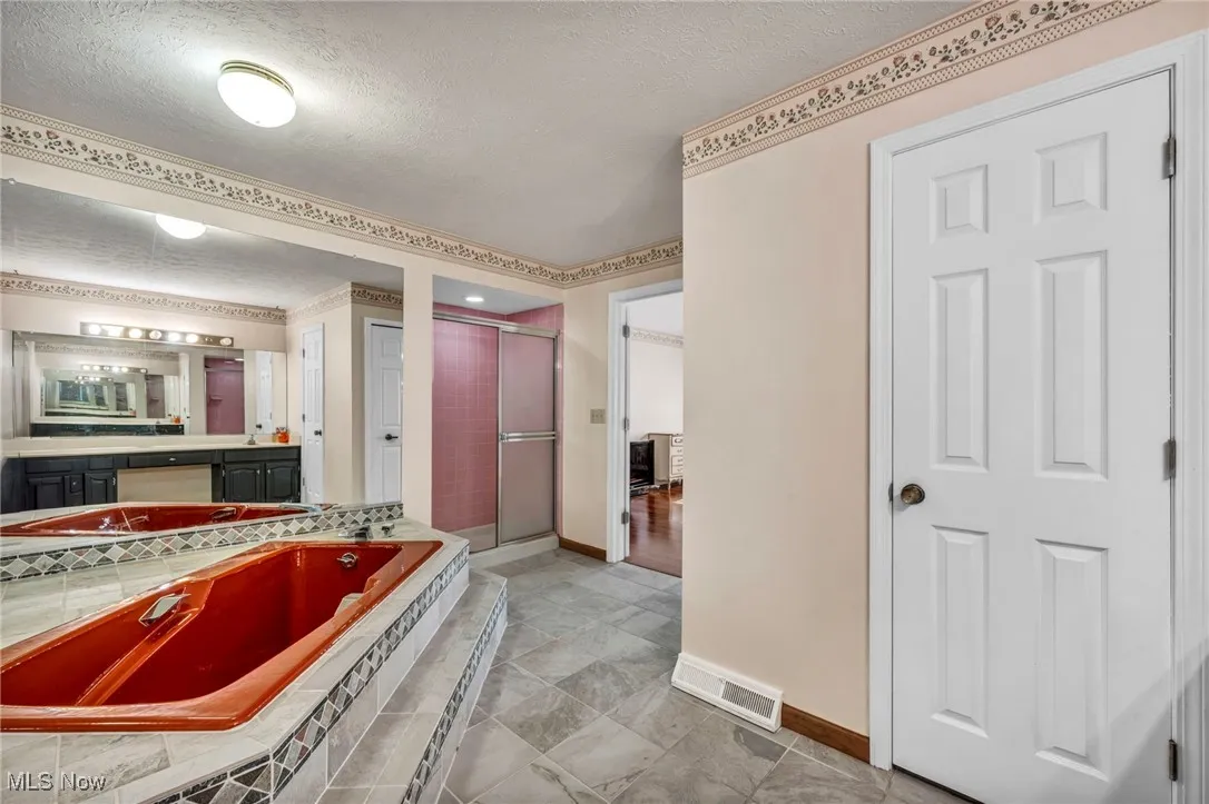 Full bath featuring a stall shower, a textured ceiling, vanity, and a garden tub