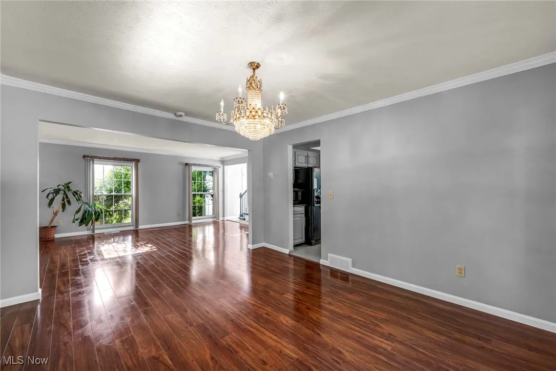 Unfurnished room featuring a chandelier, wood finished floors, and crown molding
