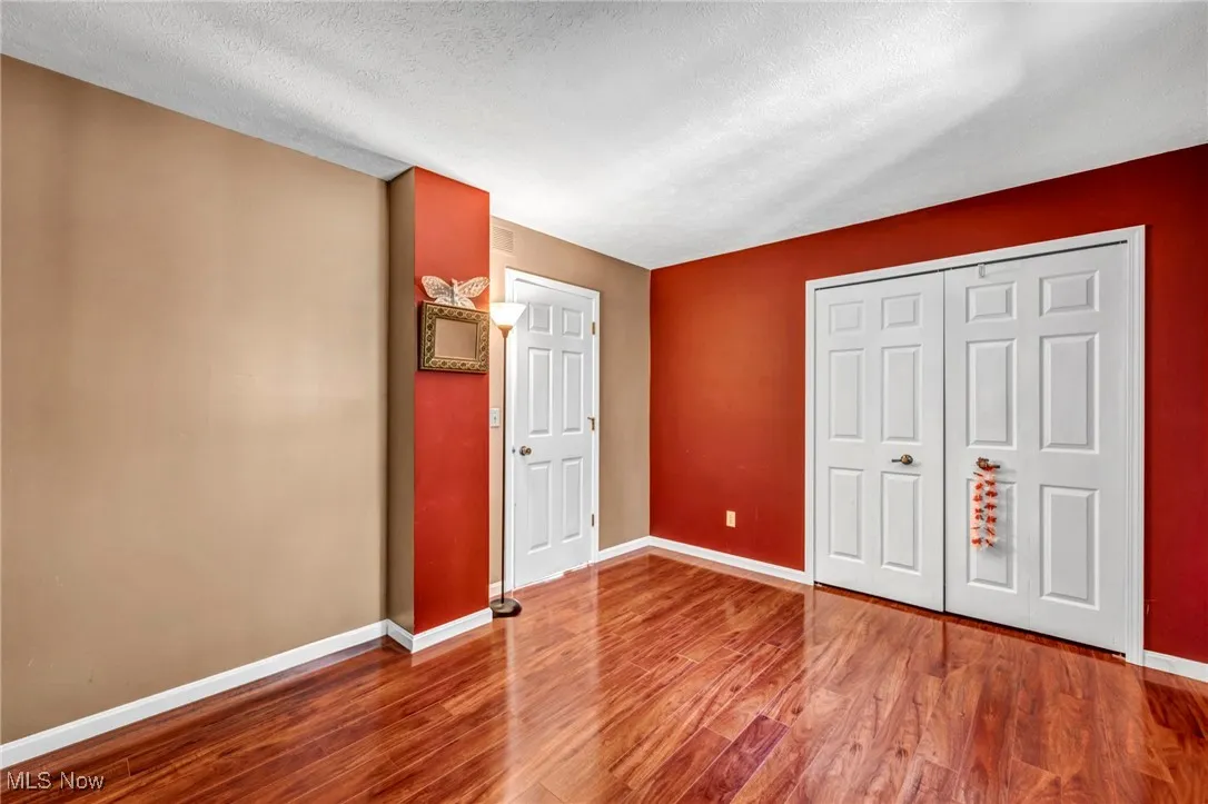 Unfurnished bedroom featuring wood finished floors, a textured ceiling, and a closet