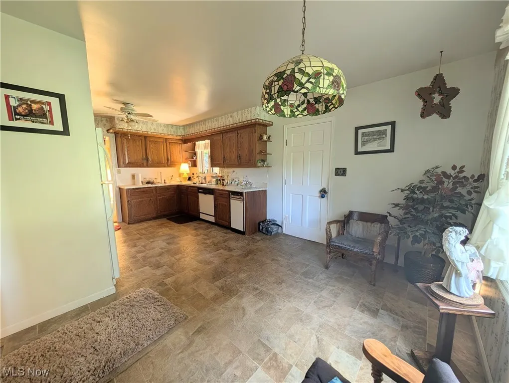 Kitchen featuring stone finish flooring, light countertops, open shelves, brown cabinets, and ceiling fan