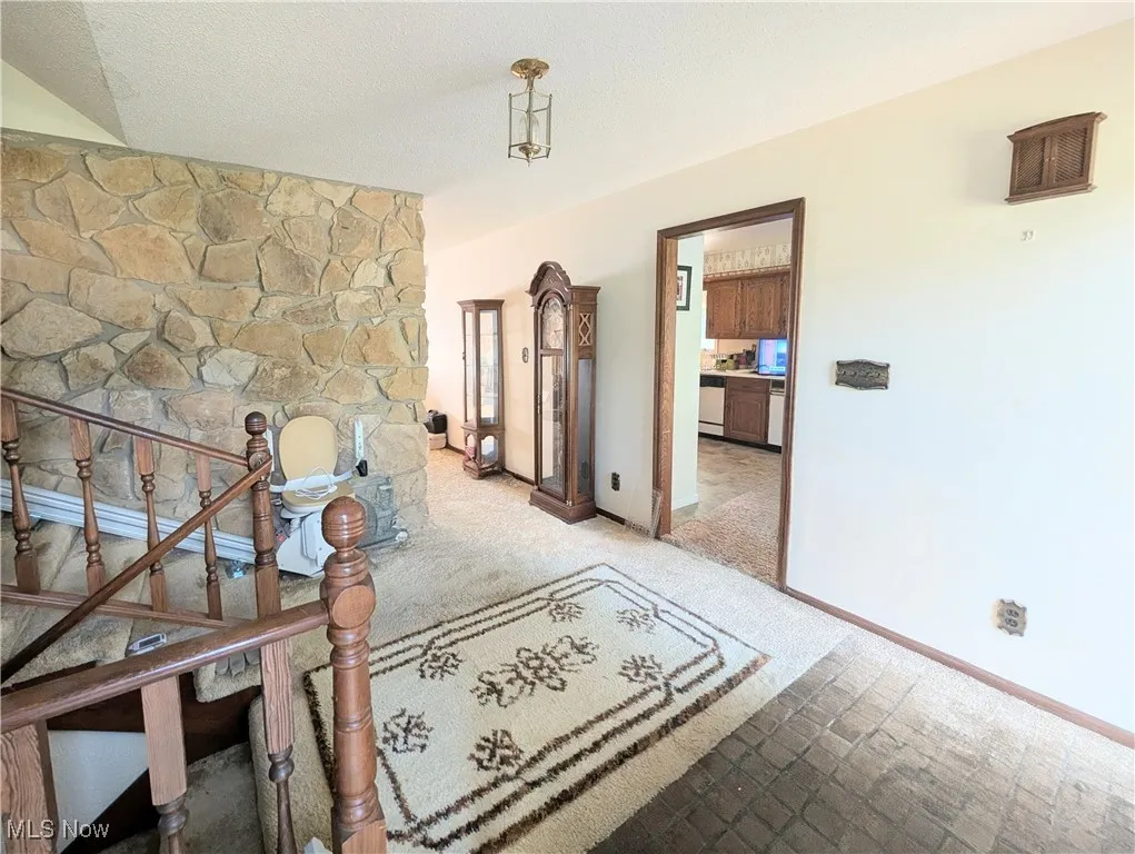 Hall with carpet floors, stairway, and a textured ceiling